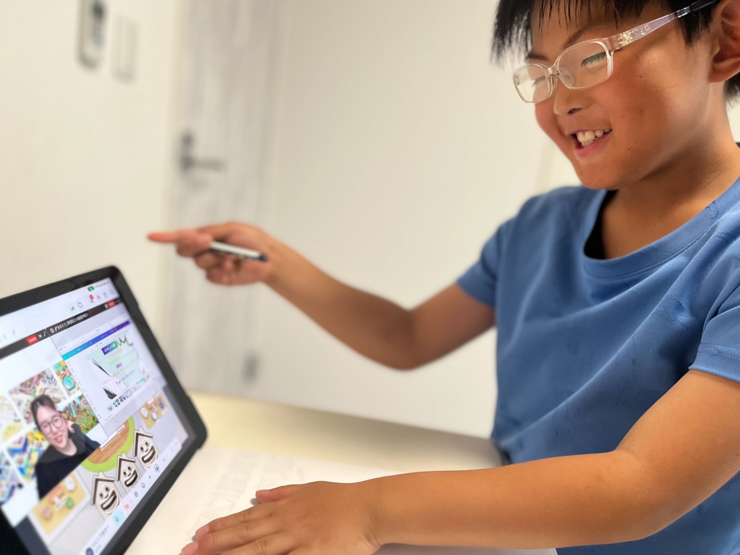 タブレットのオンライン授業で笑顔で発言している小学生