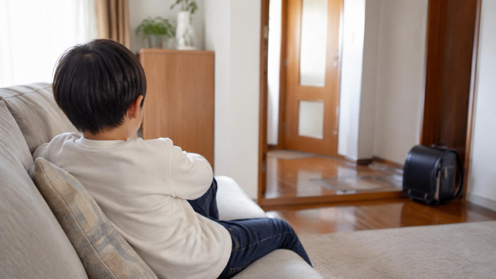 学校から帰宅し、家のソファで静かに休む小学生