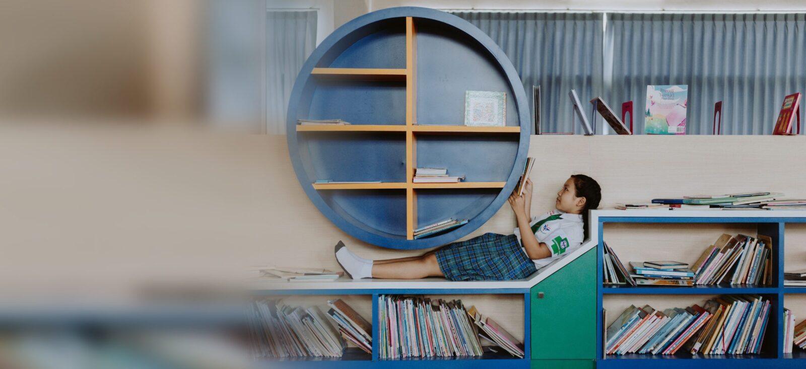 図書スペースで寝ころんで本を読む女の子