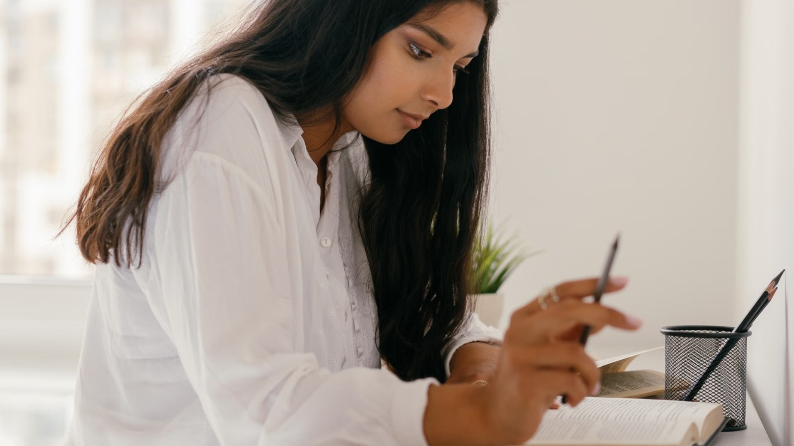 A teenager studying at a desk by a window