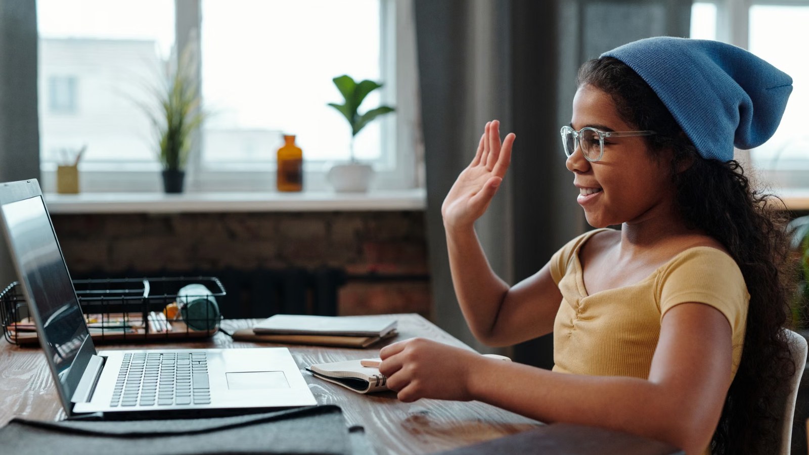 A child waving to classmates during an online class