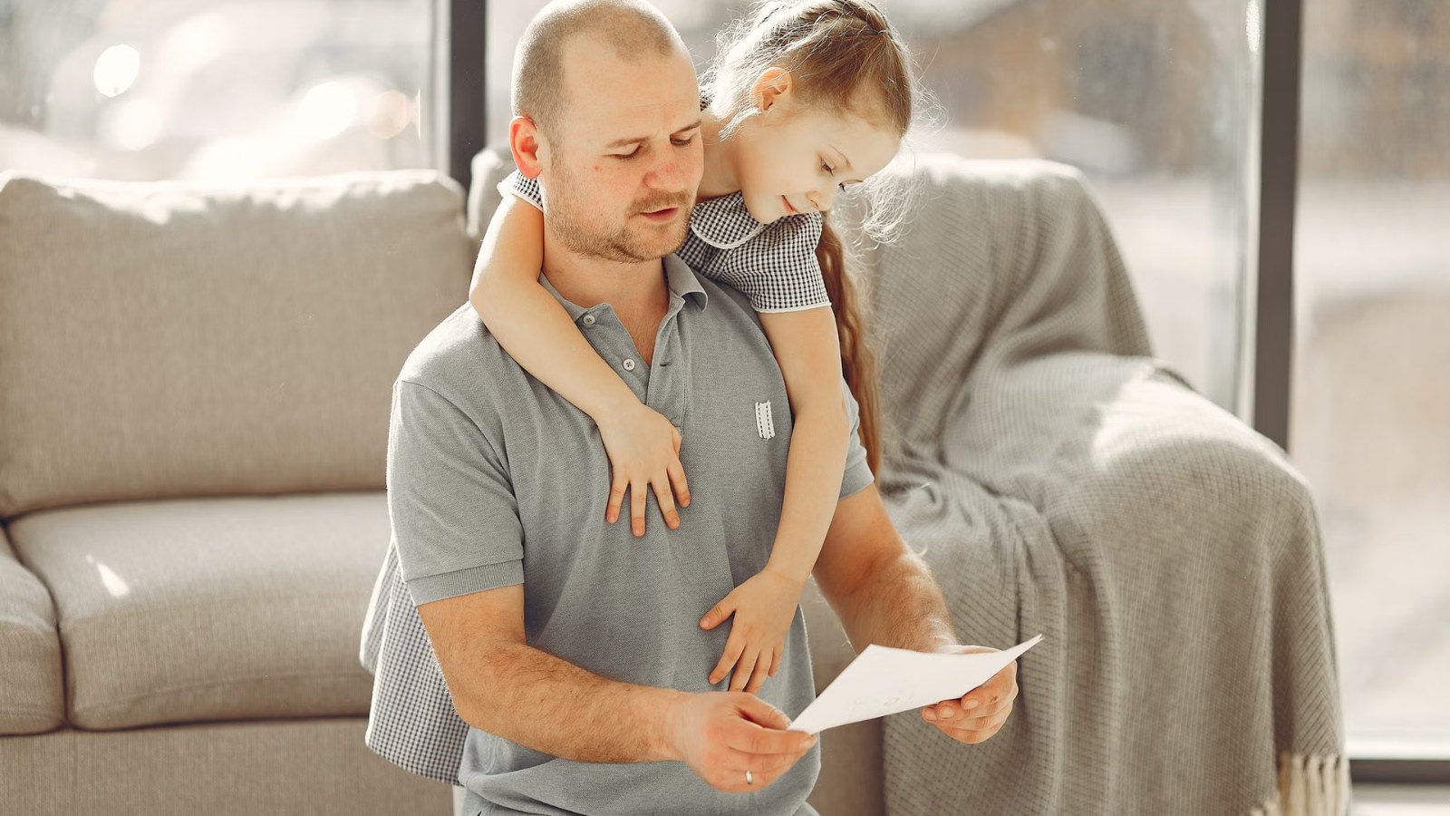 A parent and child looking at papers together on the sofa