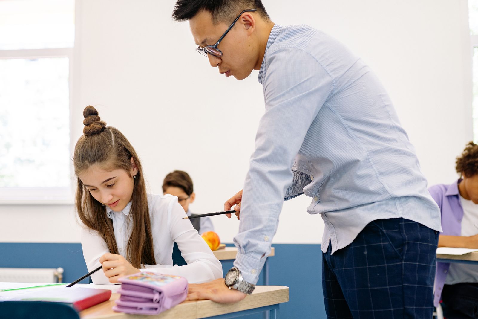 A teacher working one to one with a primary school pupil at a bright classroom desk