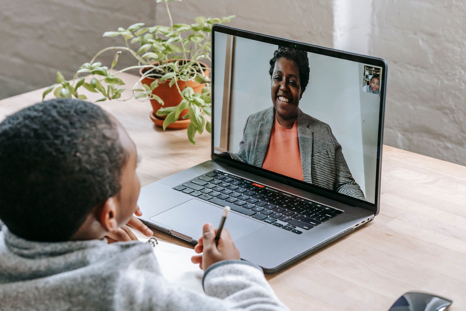 A child smiling at a laptop during a small online lesson at home