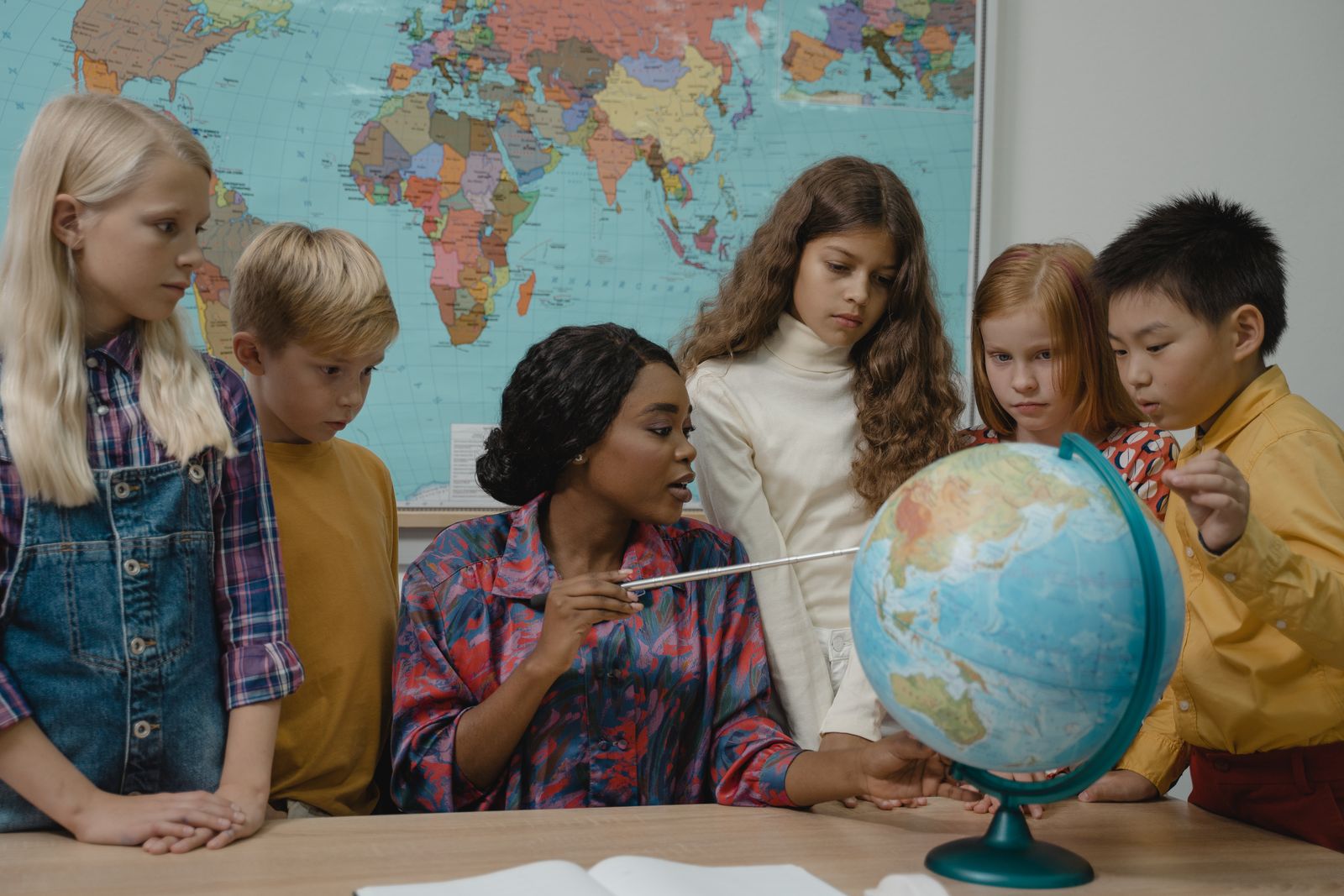 地球儀を囲んで学ぶ子どもたちと先生のイメージ