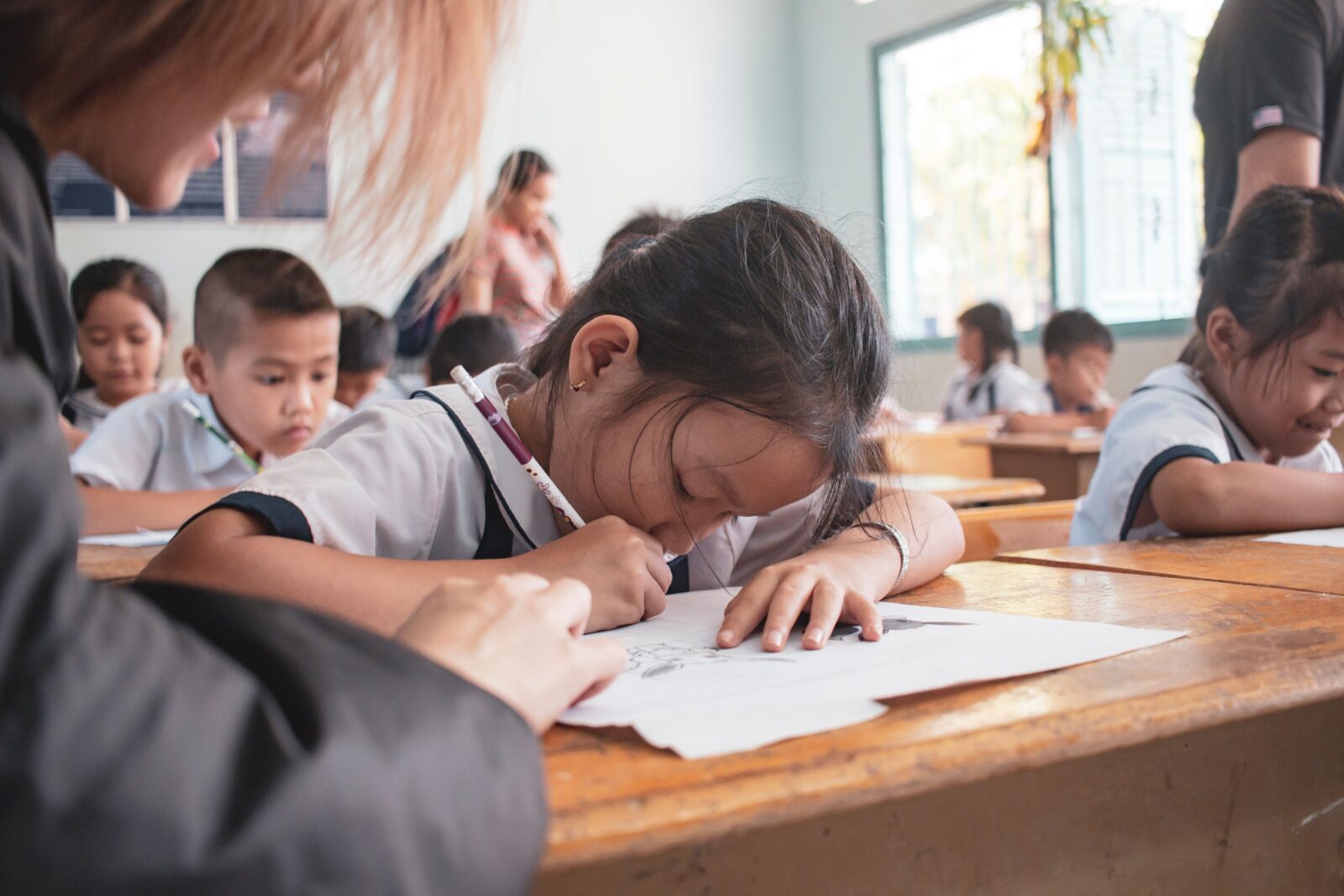 教室の机に向かってノートに書き込む小学生たち