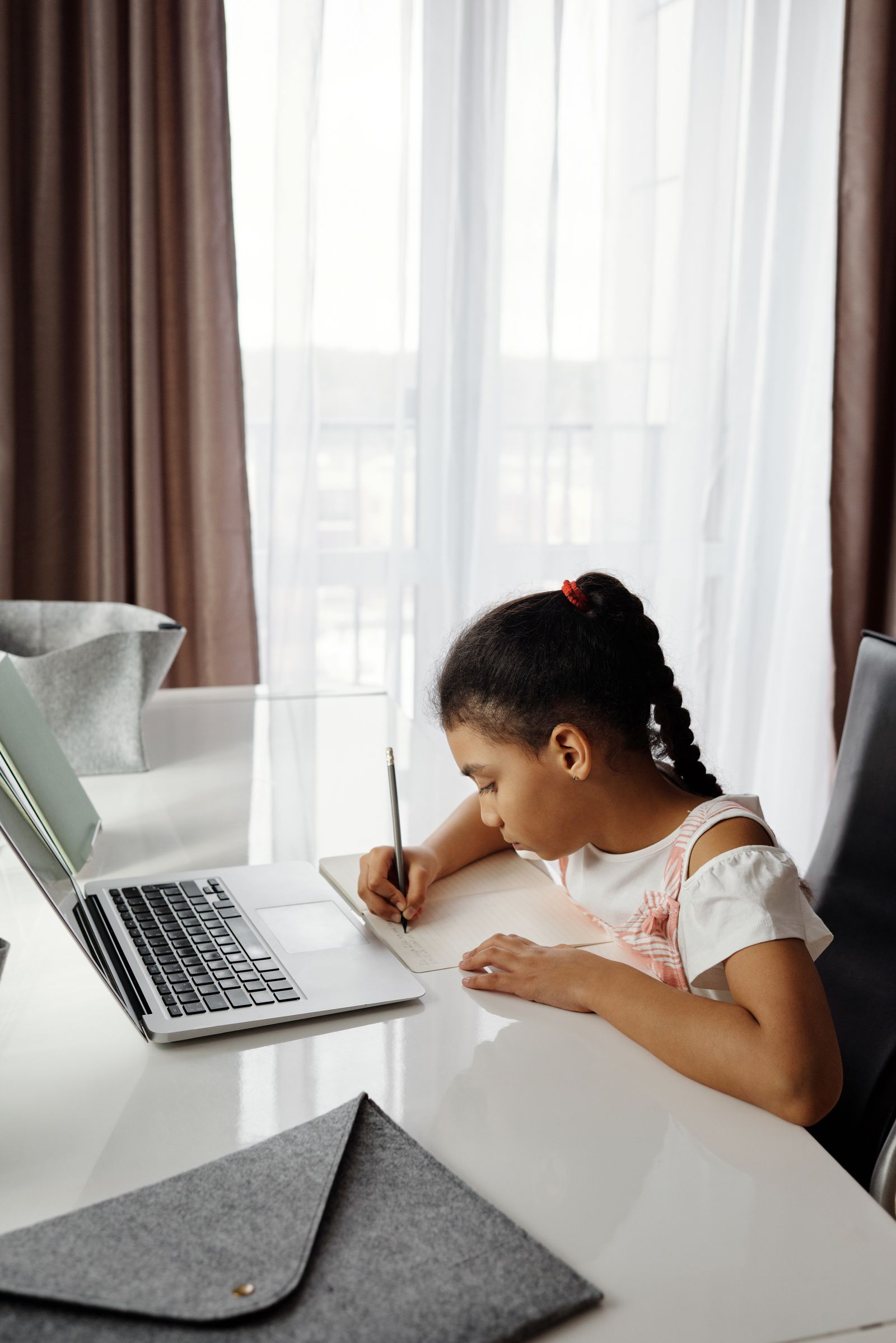 自宅の机でノートパソコンを開いてオンライン授業を受ける子ども