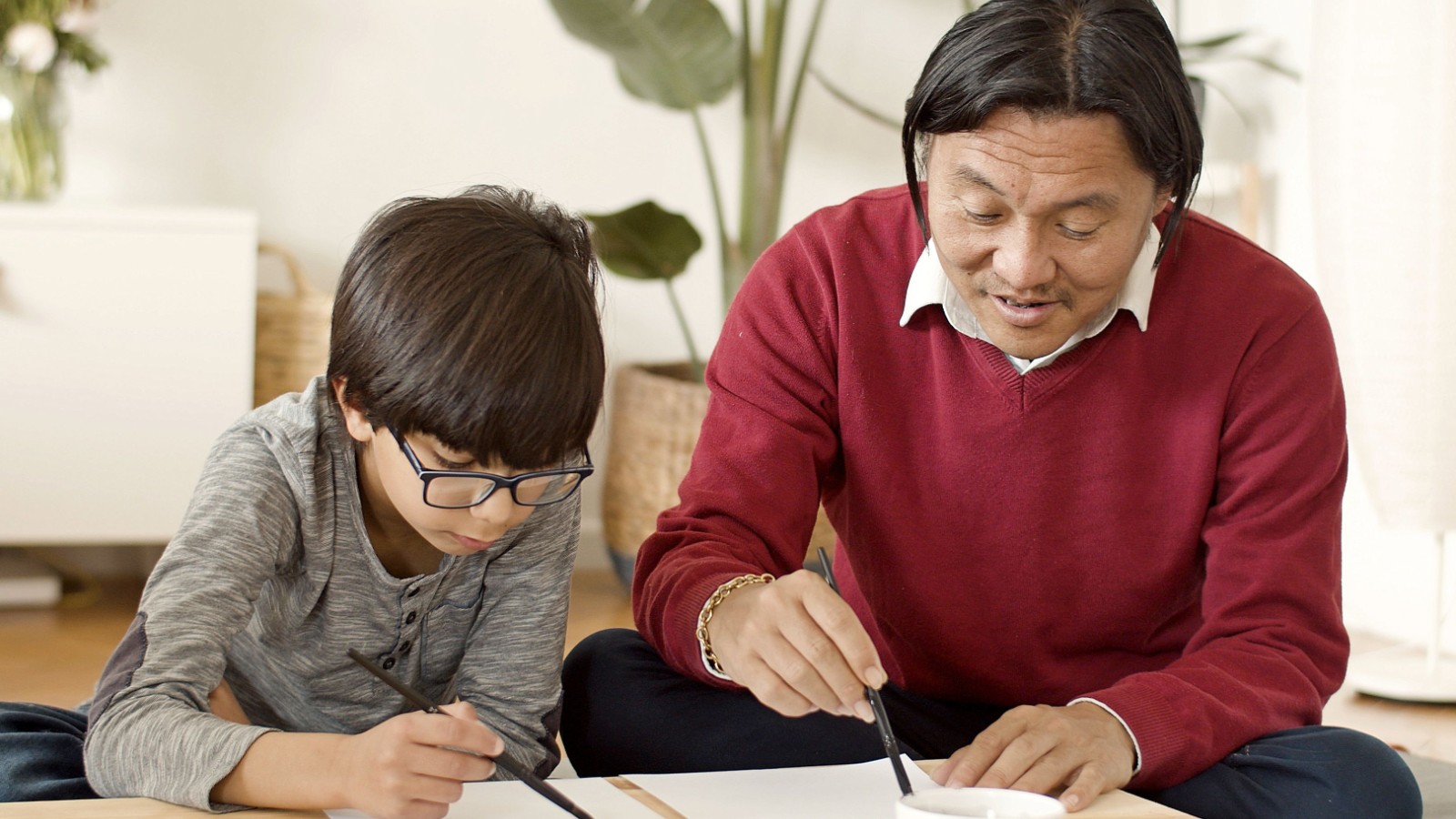 大人に教わりながら書道を練習する男の子