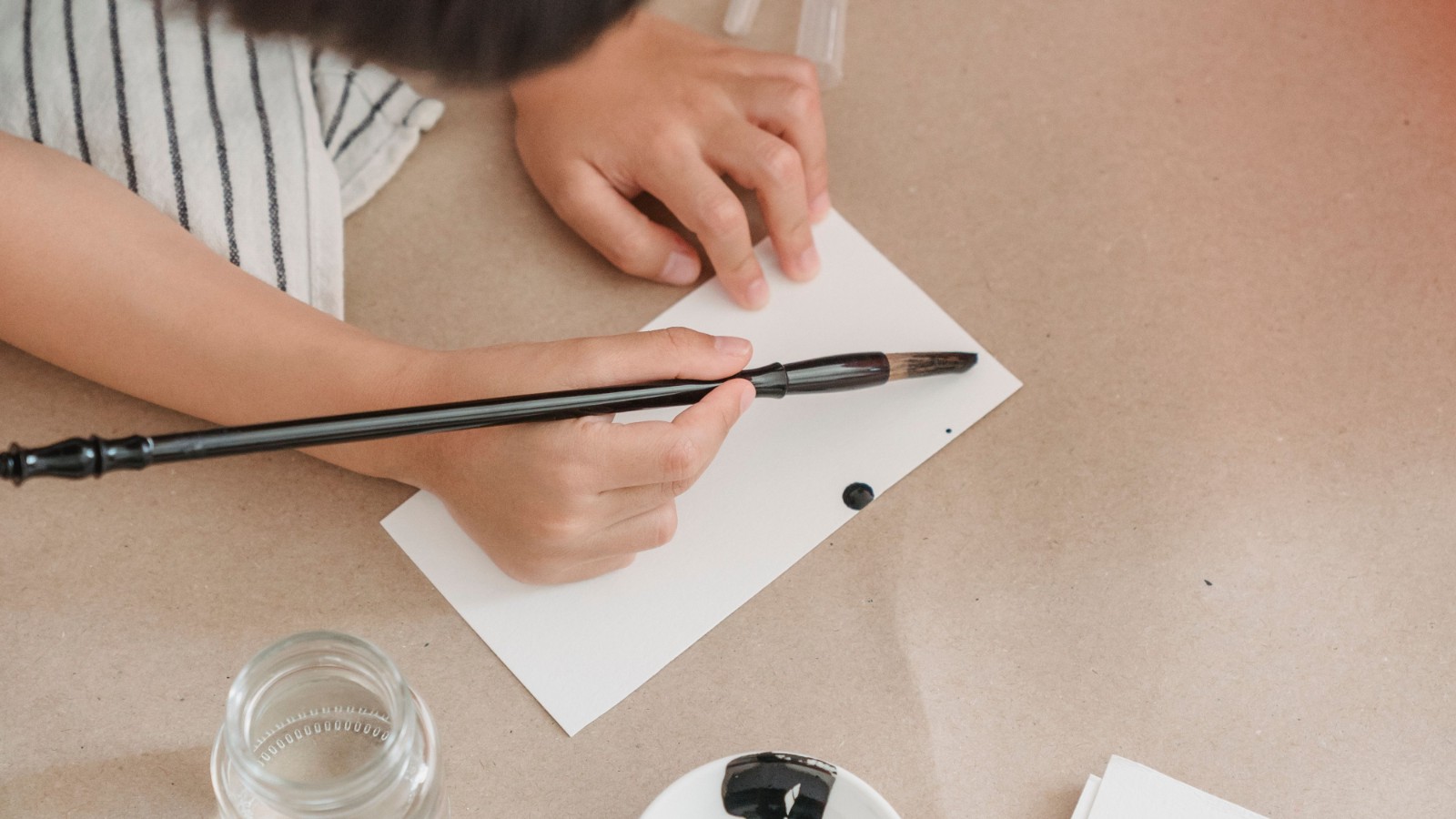 筆を使って白い紙に書く子ども