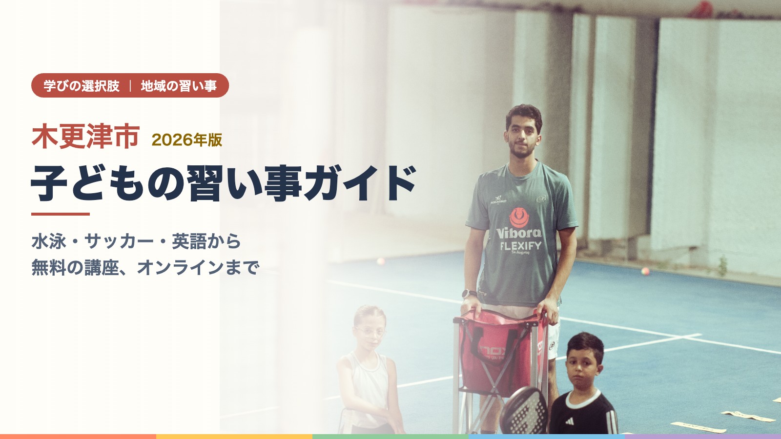 屋内のテニスコートでコーチが子どもにテニスを教えている場面