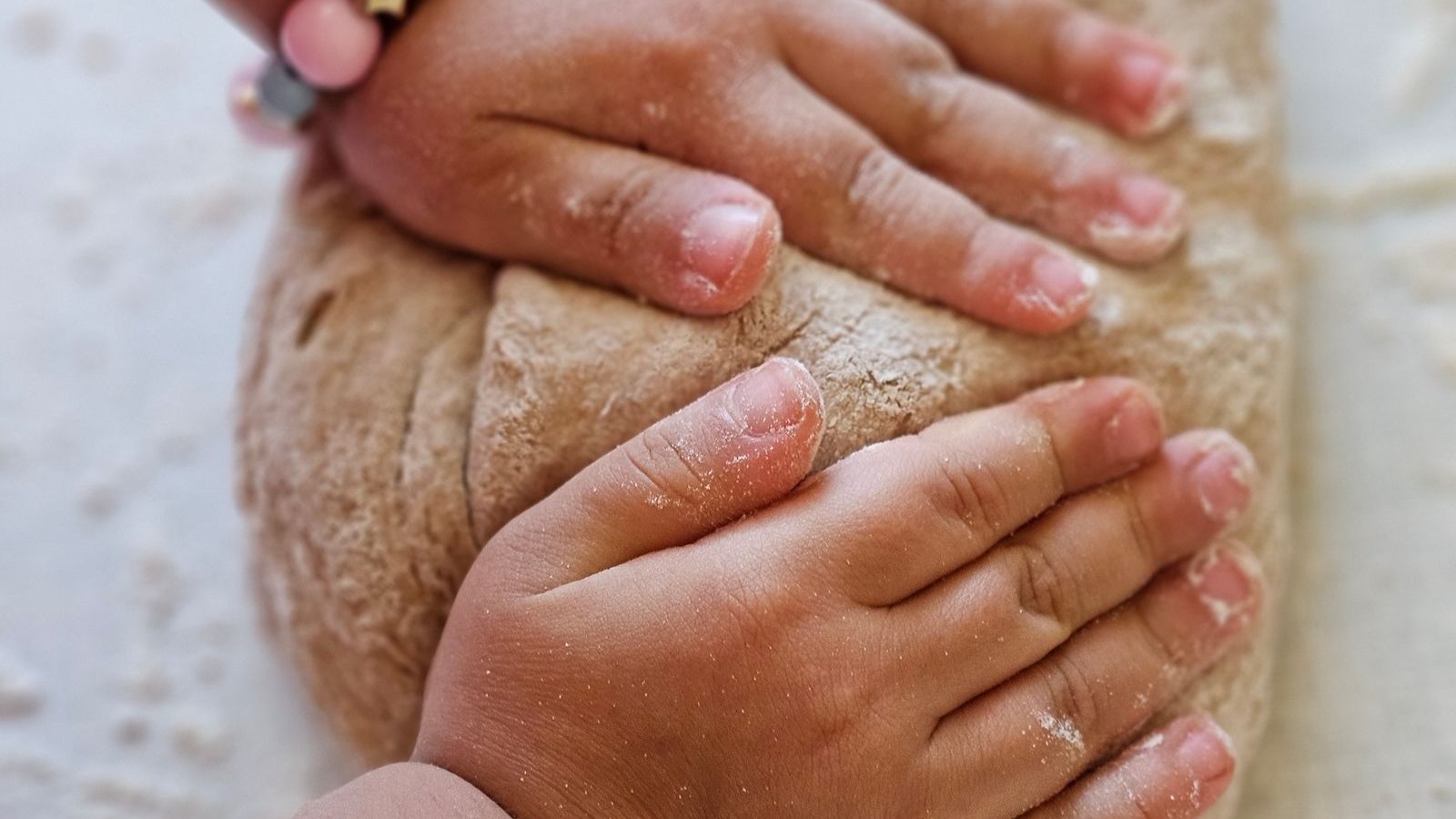 ボウルの生地をこねる子どもの手元