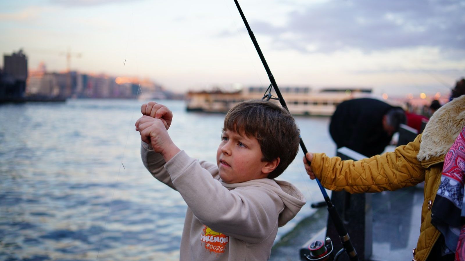 海辺で釣り竿を持つ子ども