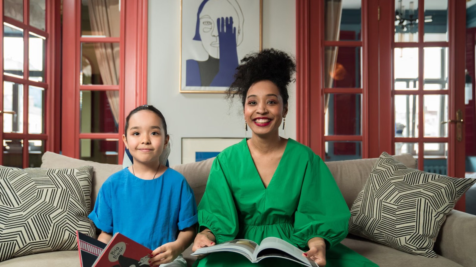 A parent and child reading together on the sofa