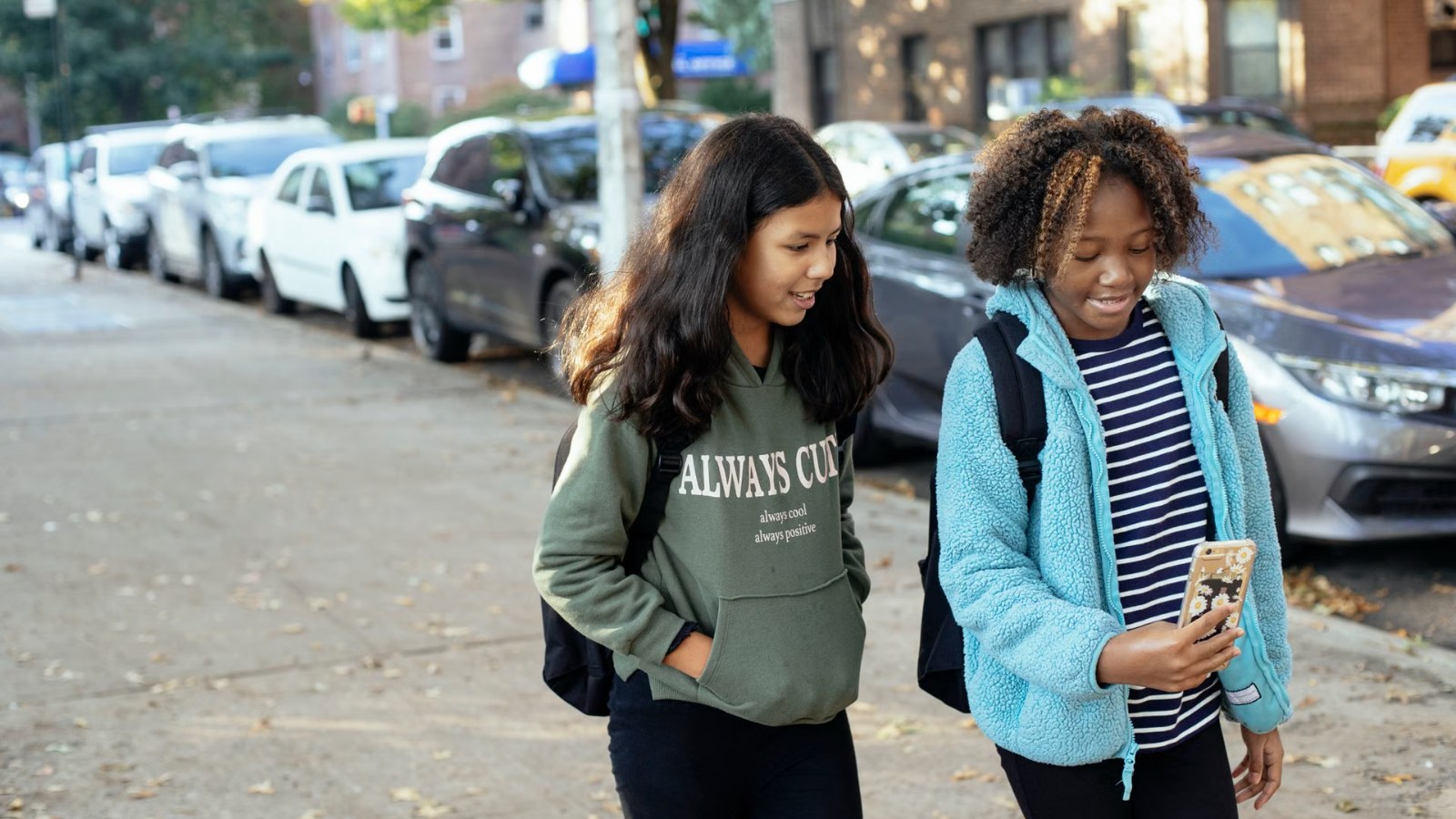 Two girls with school bags walking and chatting
