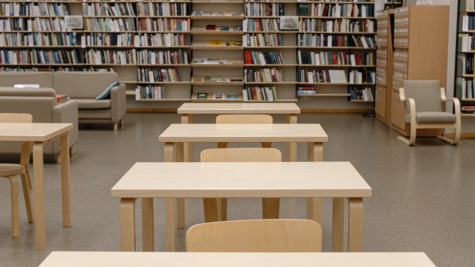 図書館の閲覧席に並ぶ木のテーブルと椅子