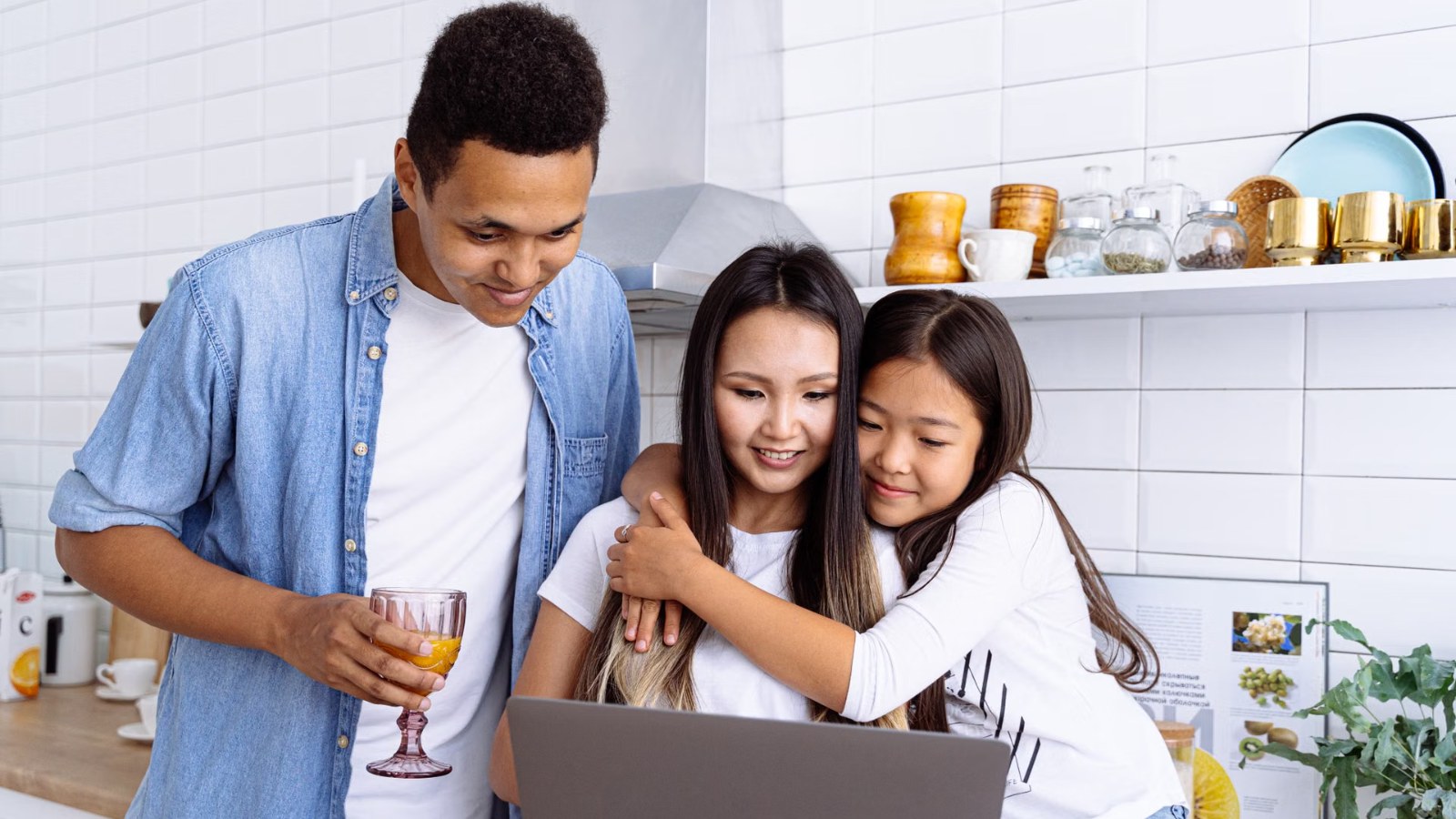 A family looking at a laptop together in the kitchen