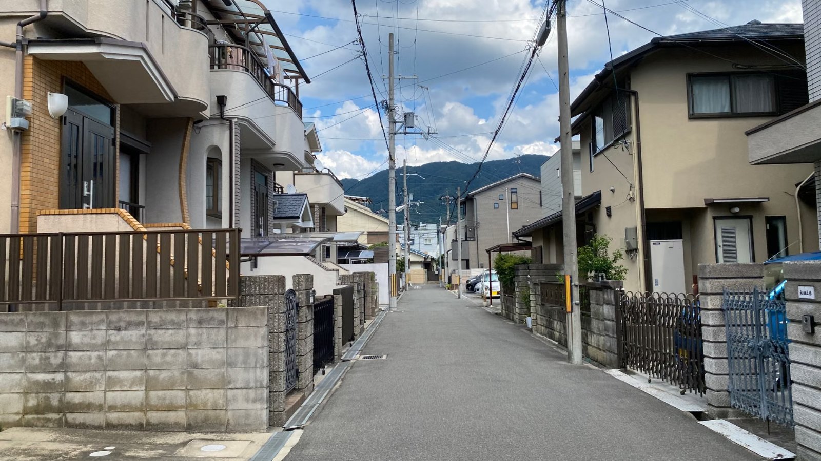 青空と山並みが見える住宅街の道