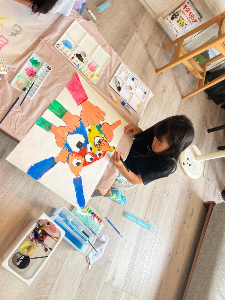 大きな紙にのびのびと絵を描いている子ども