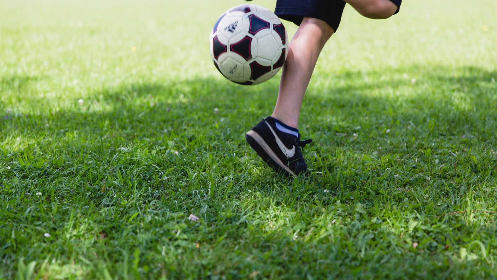グラウンドでサッカーボールを蹴る子ども