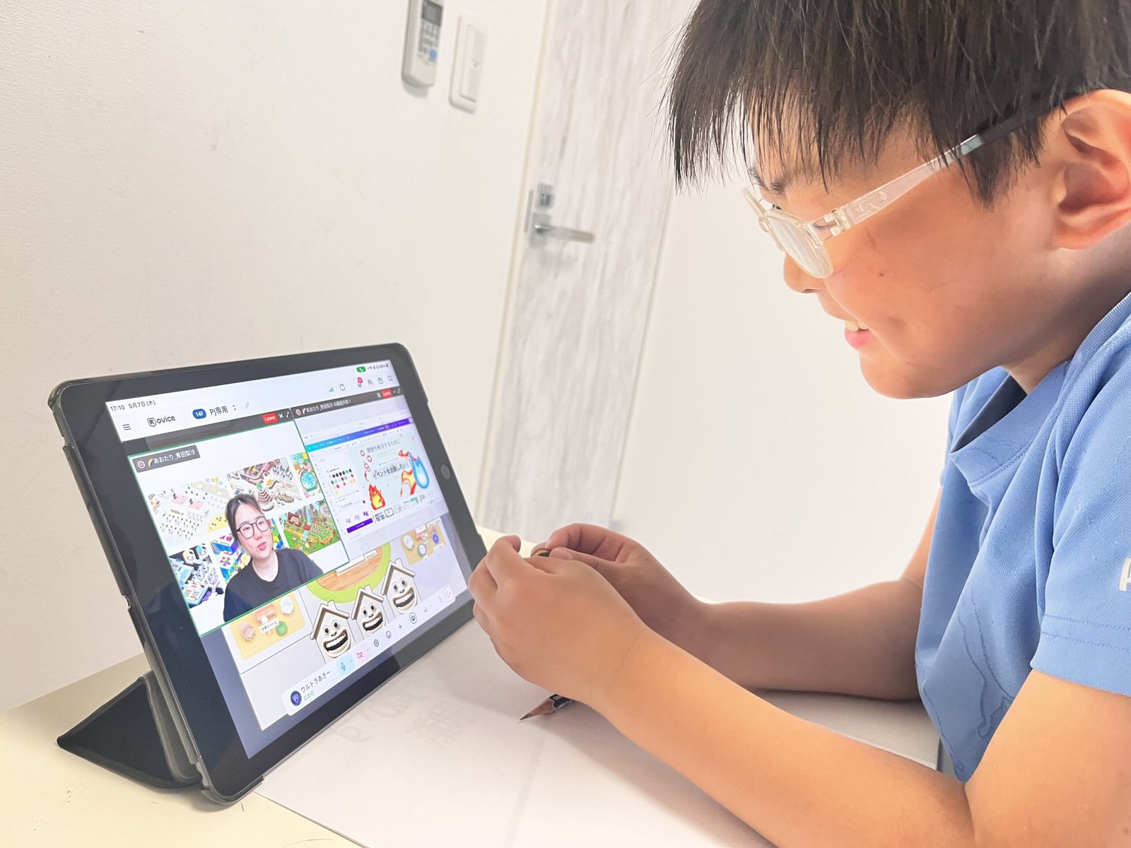 自宅の机でタブレットを開き、オンラインのクラス会議に参加する小学生