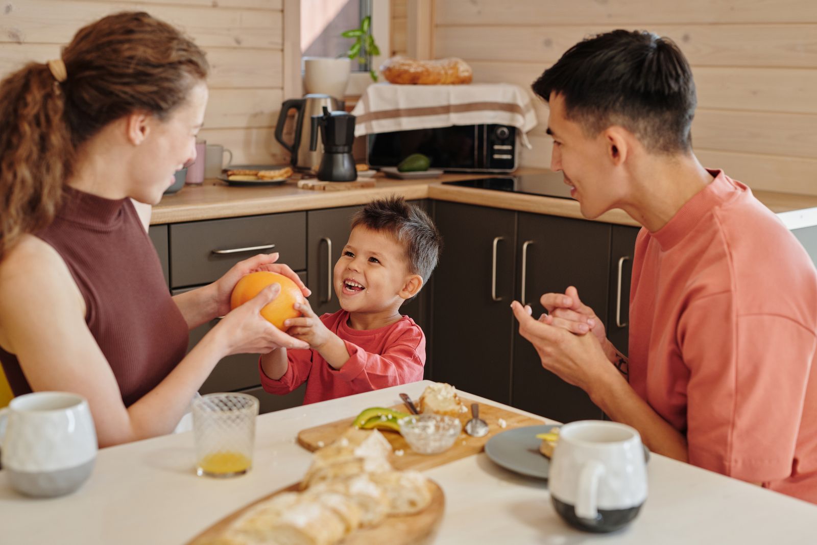 A parent and child sitting together at a kitchen table in the morning light