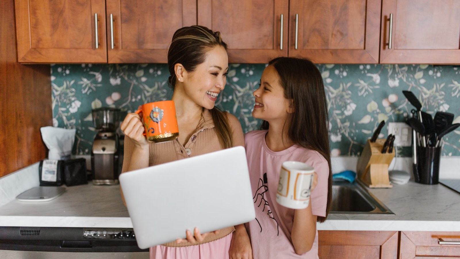 A parent and daughter laughing together in the kitchen