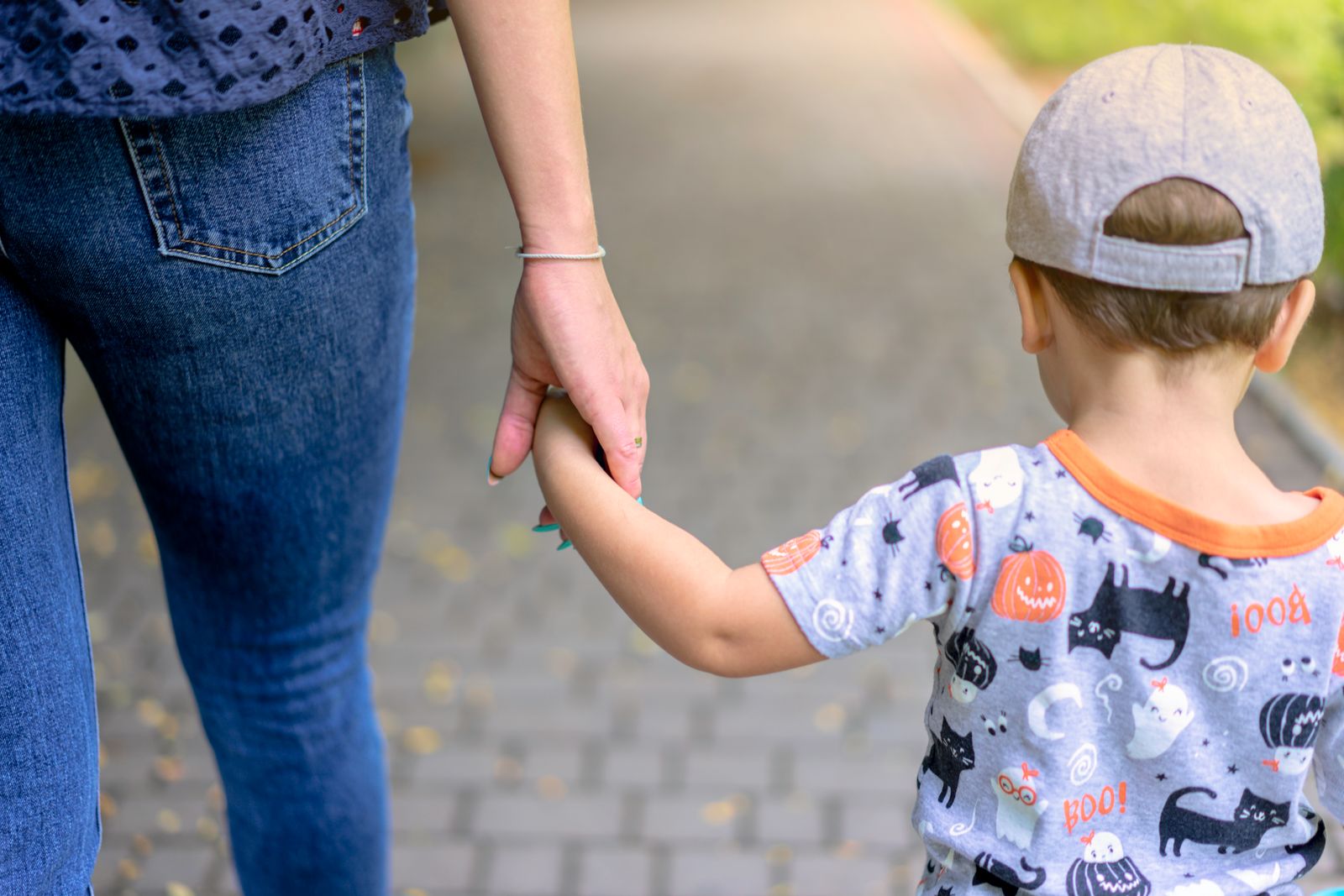 A parent and a young child walking hand in hand towards a school building in the morning