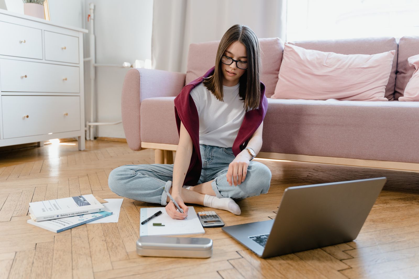 A teenager taking notes during an online class at home