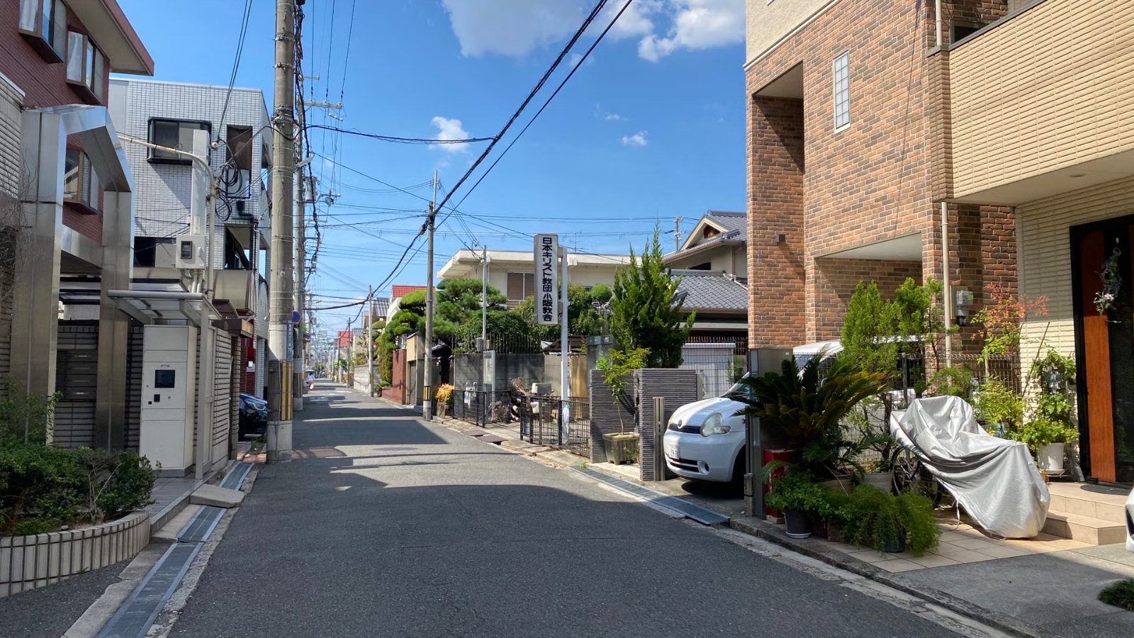 電線と青空の下の住宅街の道