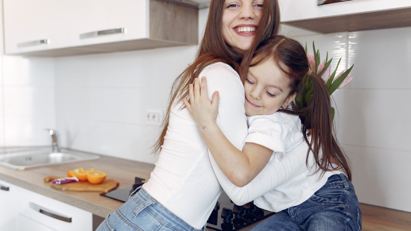 A parent hugging a child in the kitchen