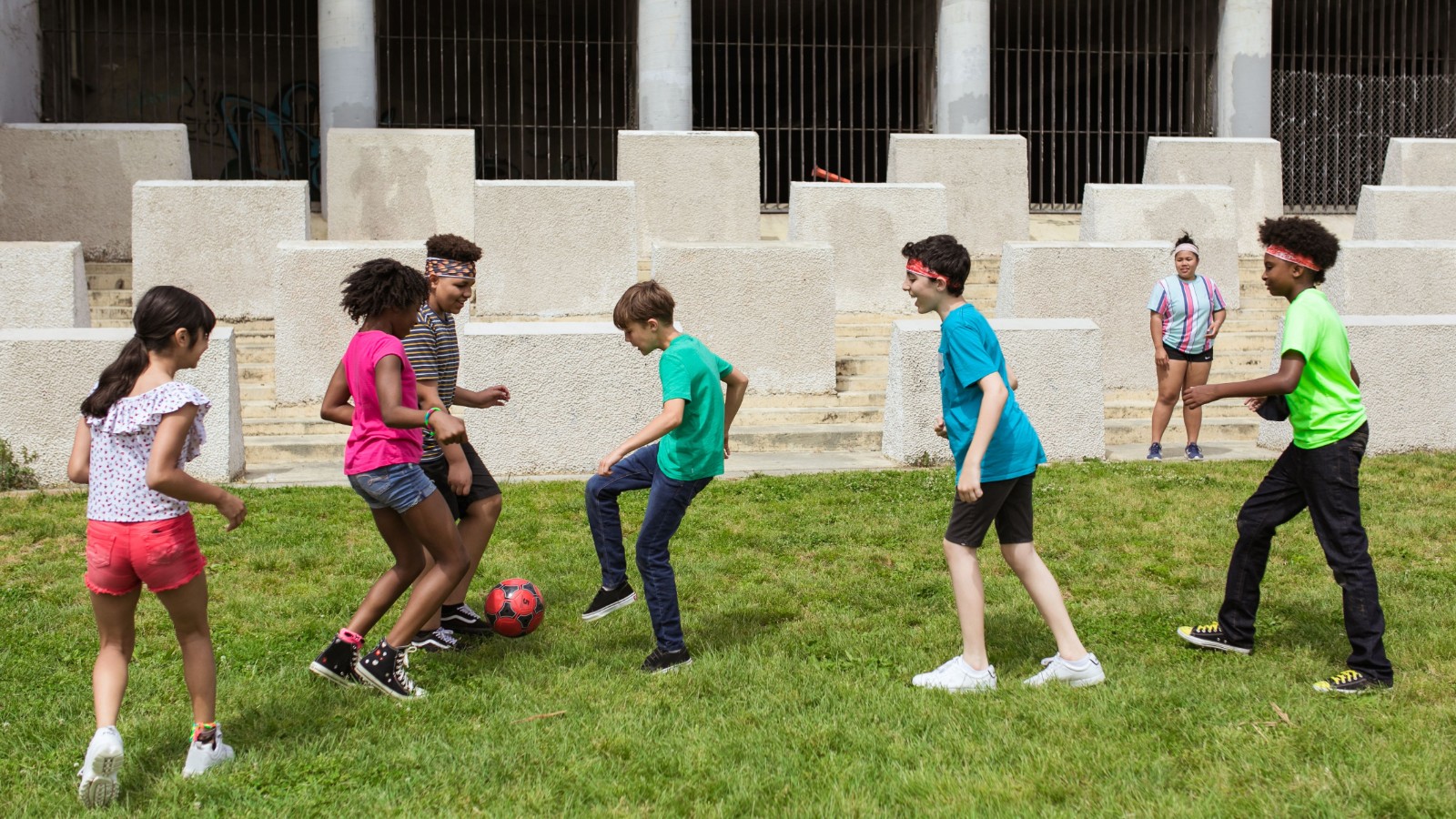 芝生のグラウンドでサッカーをする子どもたち