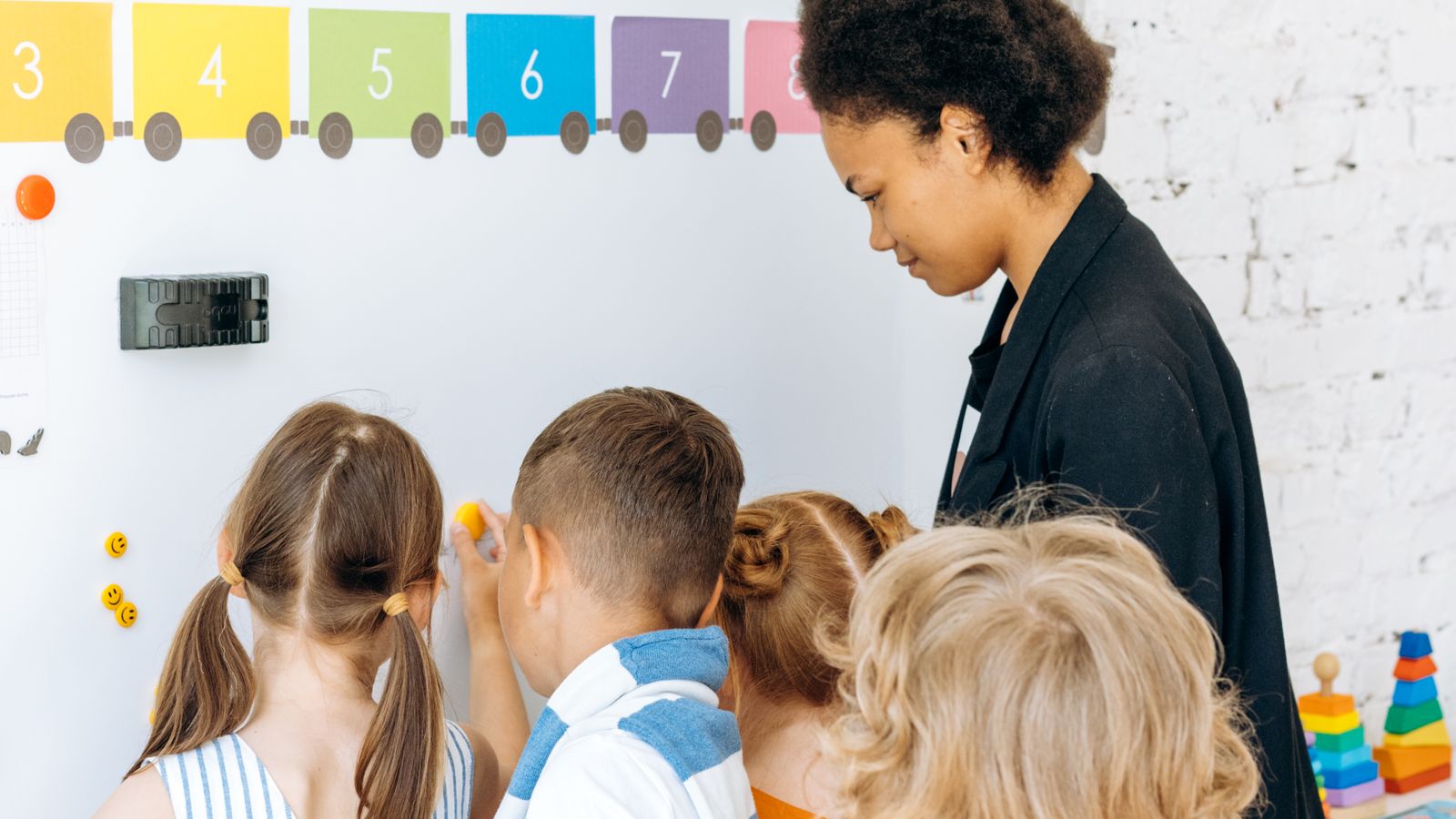 先生と一緒にホワイトボードに向かって学ぶ子どもたち