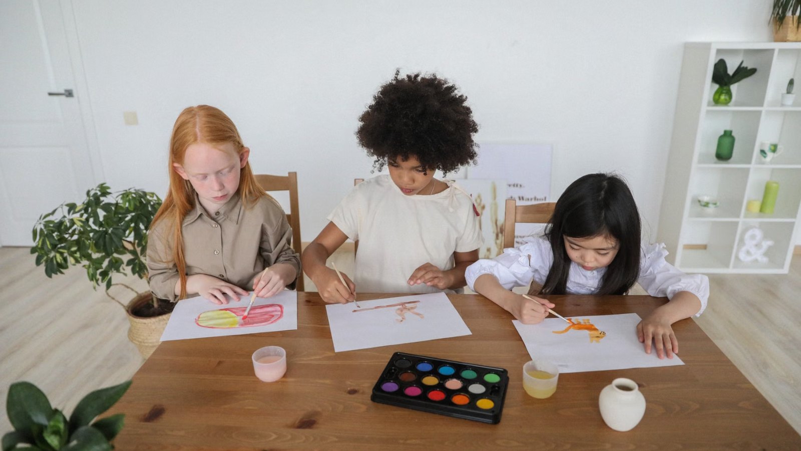 テーブルで絵の具を使って絵を描く子どもたち