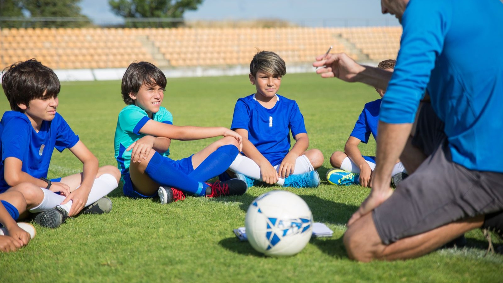 サッカーのコーチの話を聞く男の子たち