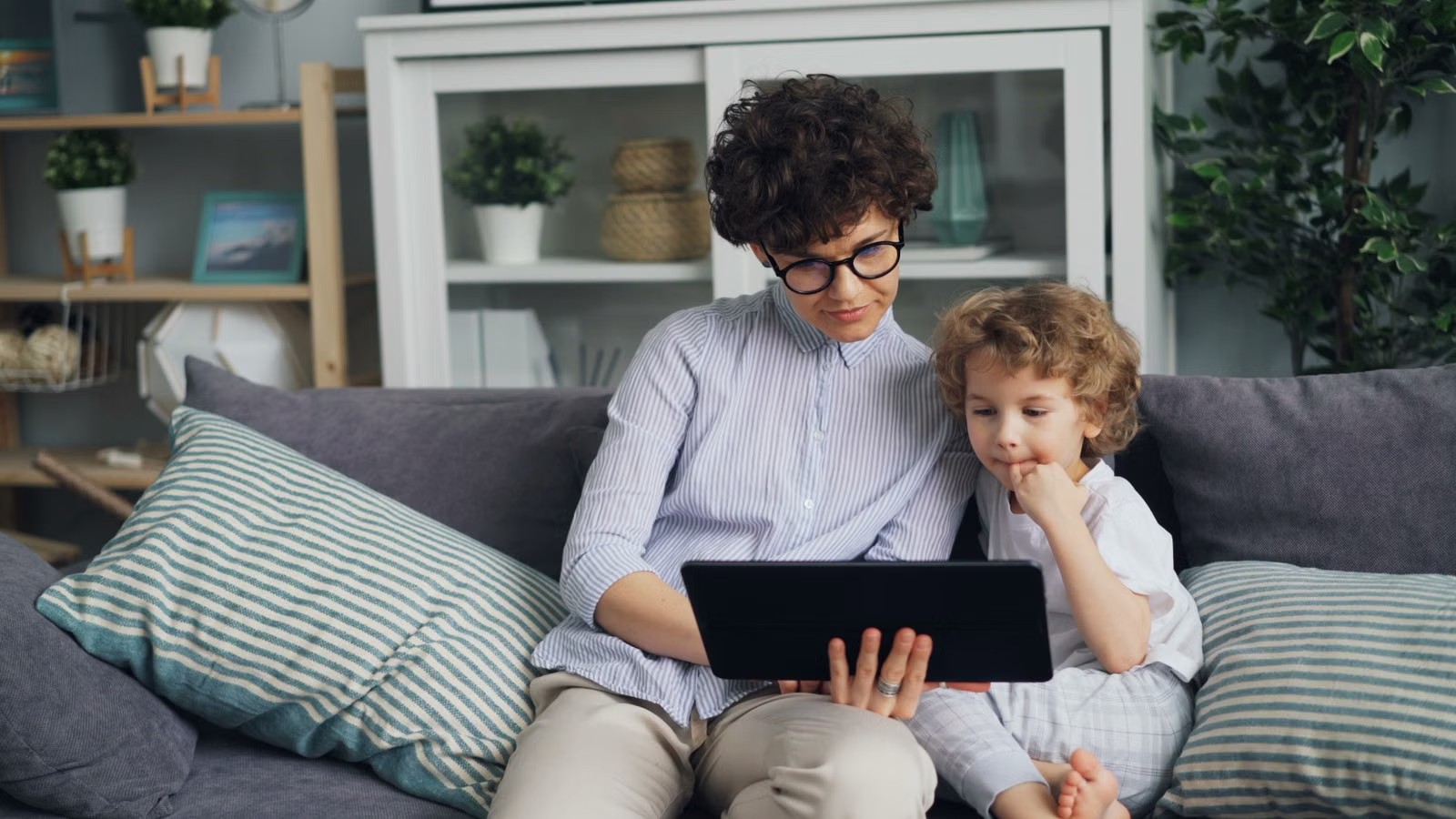 A child and a parent on a video call at home with a tablet