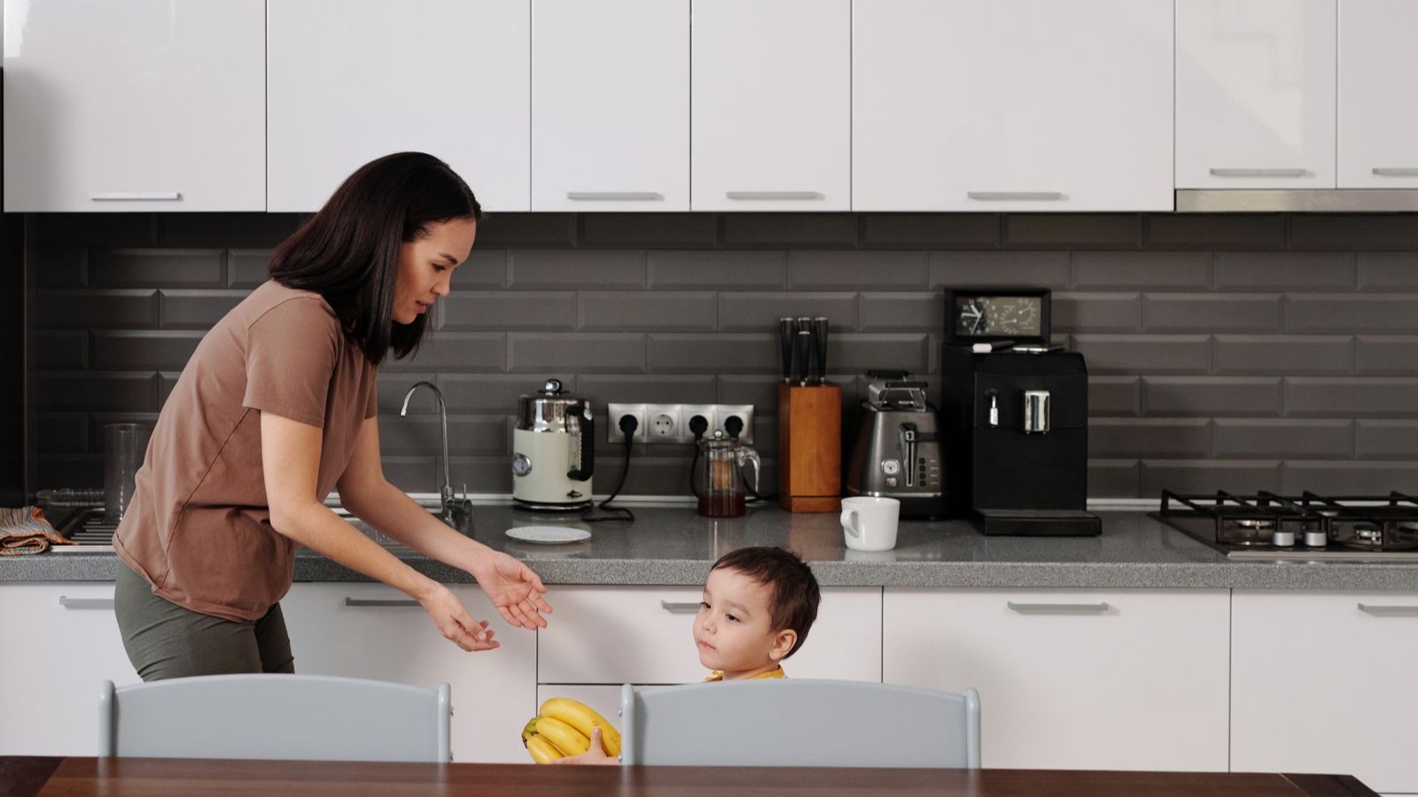 A parent and child talking together at a kitchen table at home