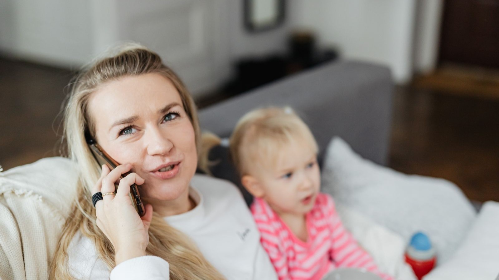 A parent on a phone call at home while a child listens nearby