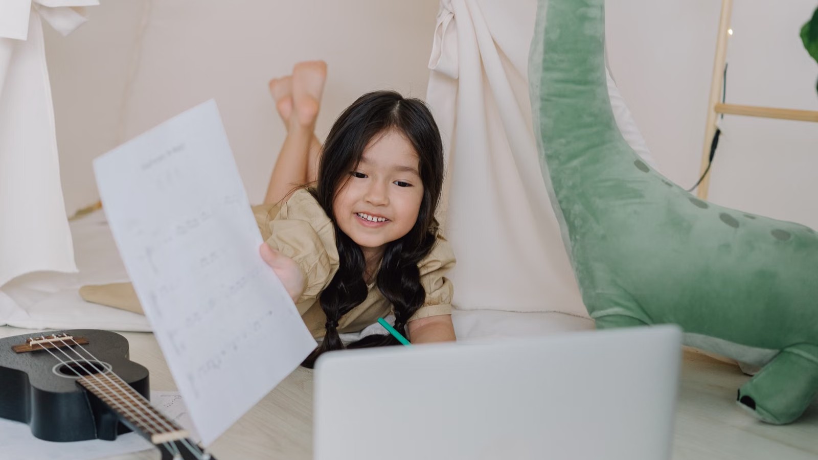 A child smiling at a laptop screen during an online class at home