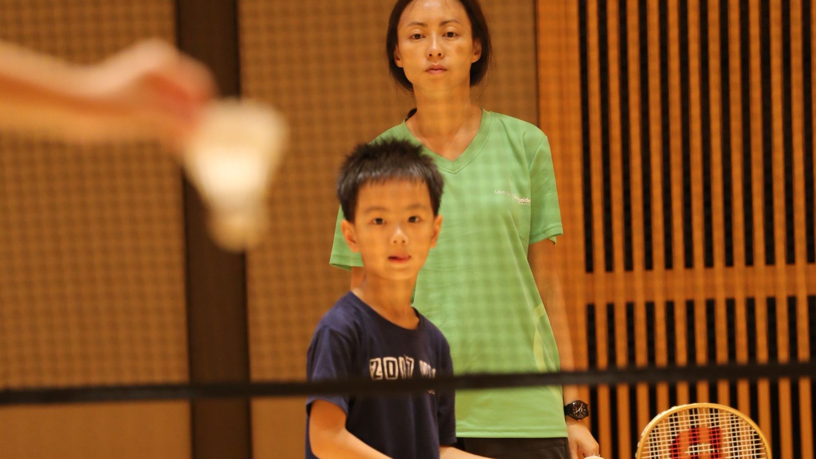 コーチと一緒にバドミントンの練習をする男の子
