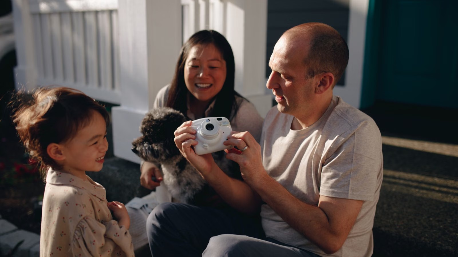 A child and her parents looking at something together in a bright room