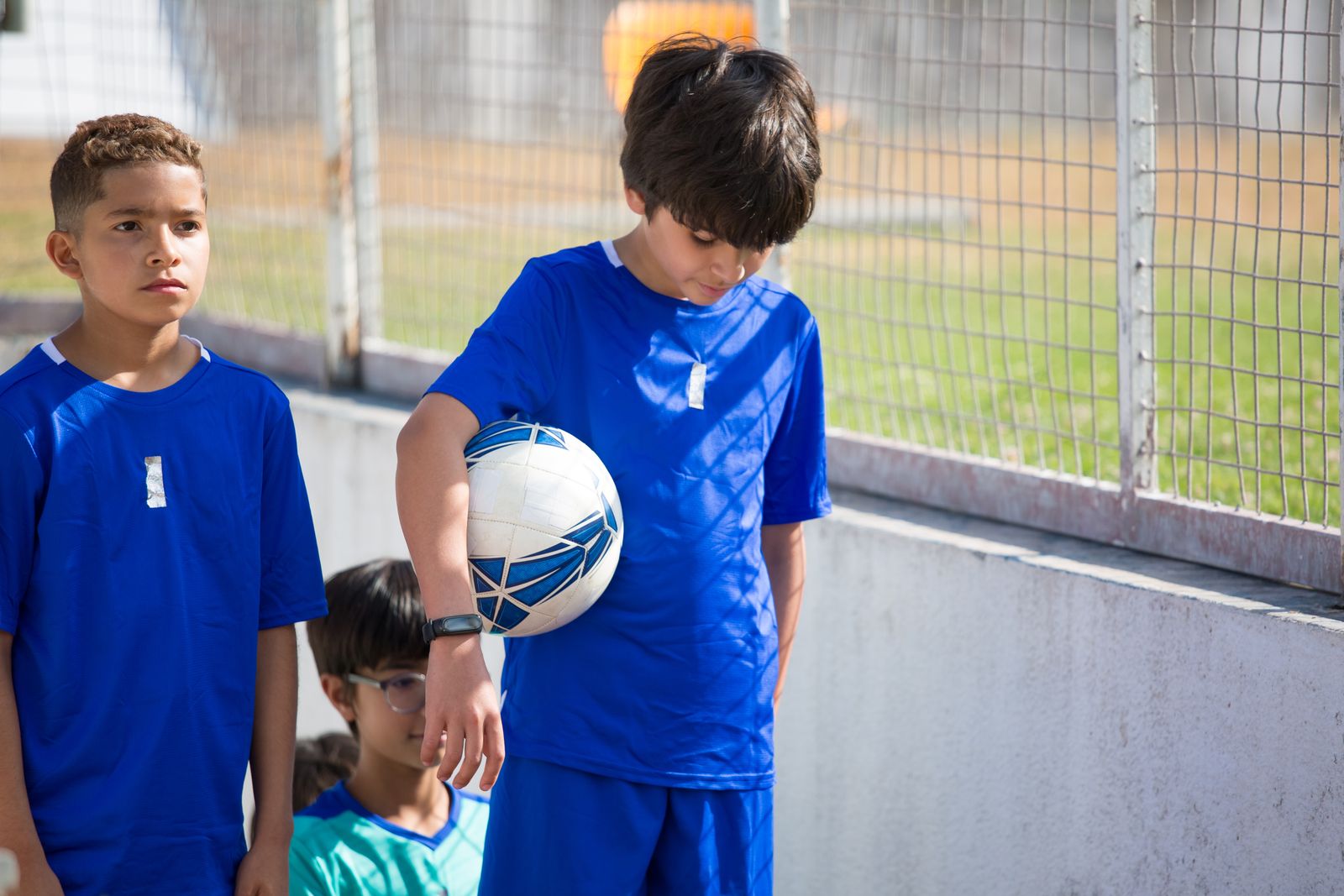 サッカーボールを持ってコーチの話を待つ子どもたち