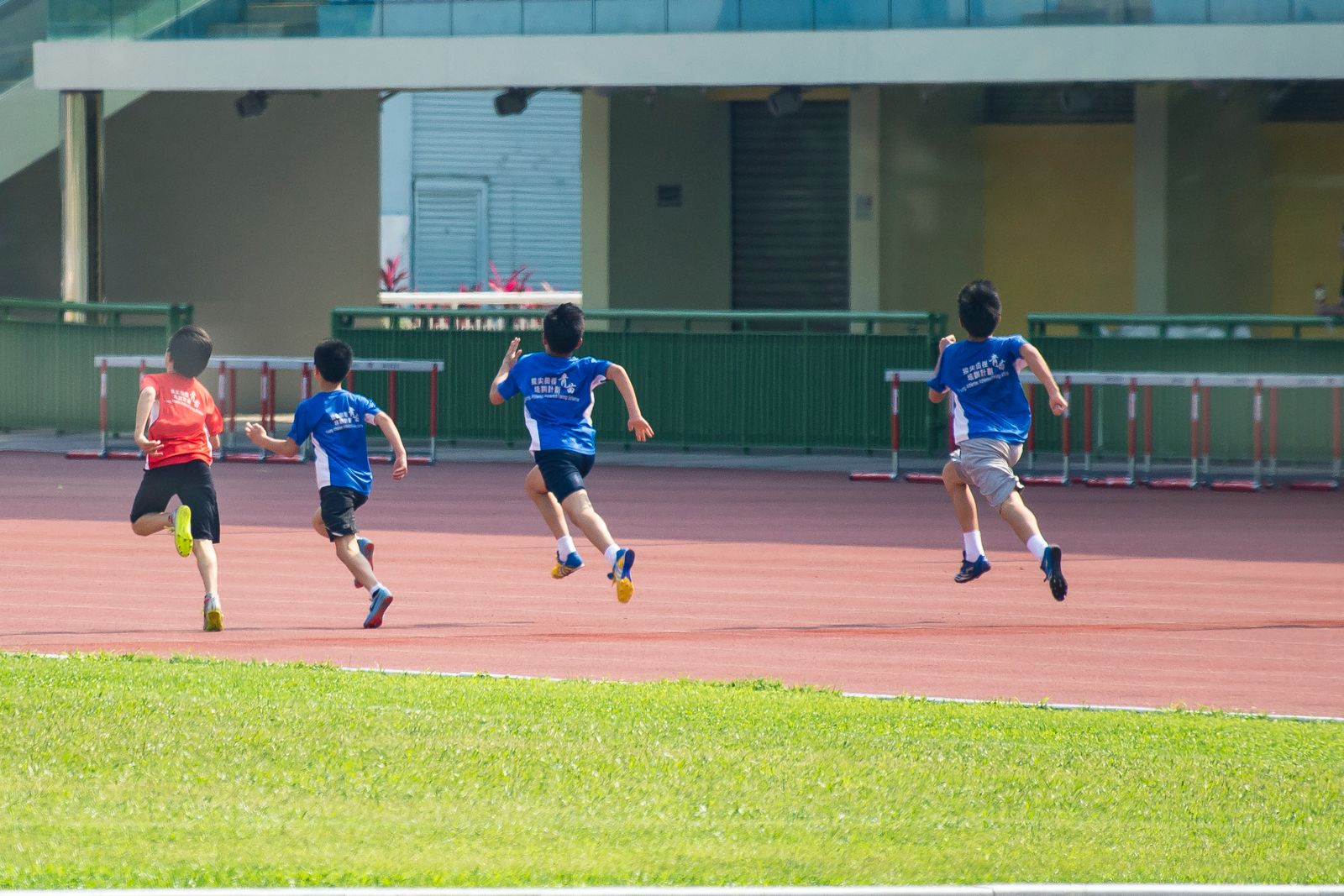 運動場のトラックを走る子どもたち