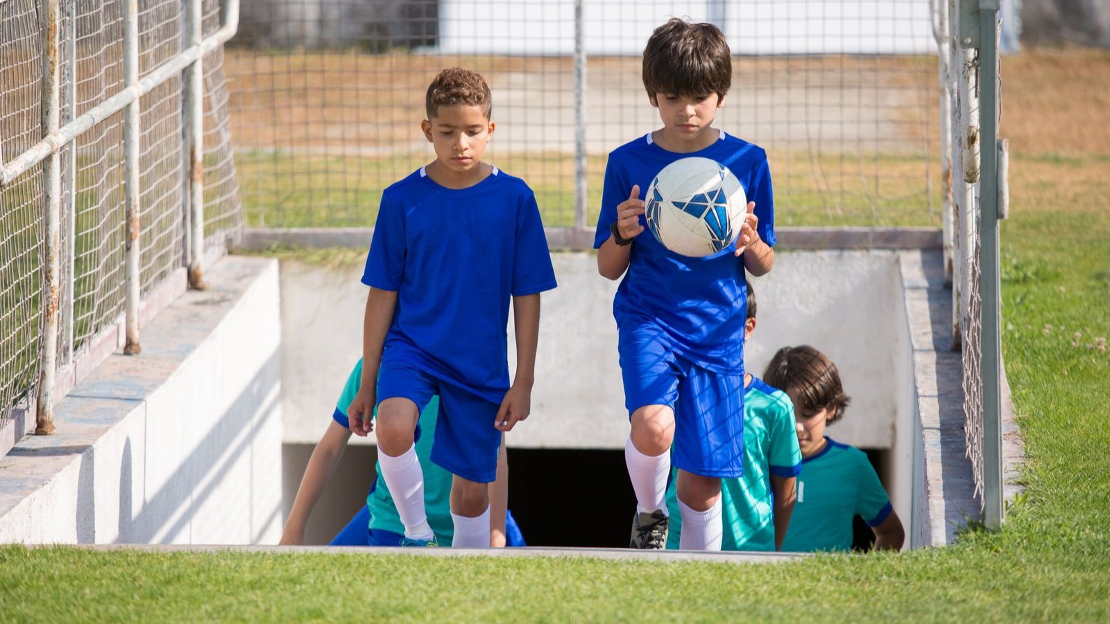 サッカーボールを持って階段を上がるユニフォーム姿の子どもたち