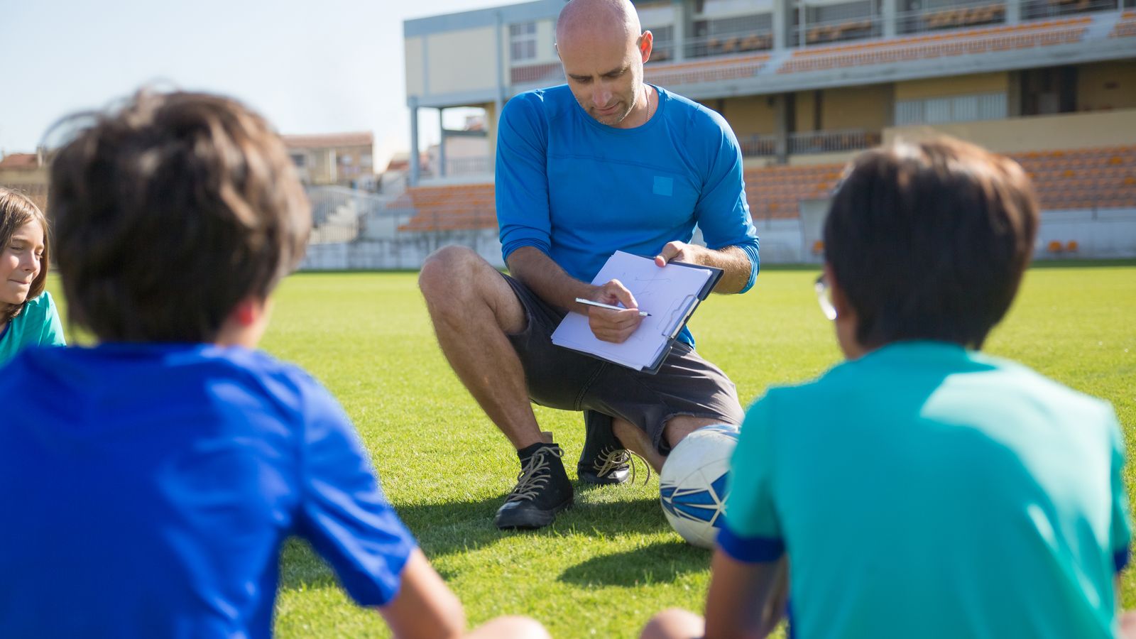 グラウンドでコーチの話を聞くサッカー少年たち