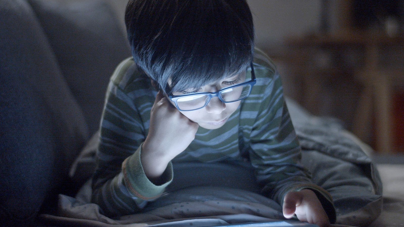 ノートに書きながらタブレットで学ぶ男の子