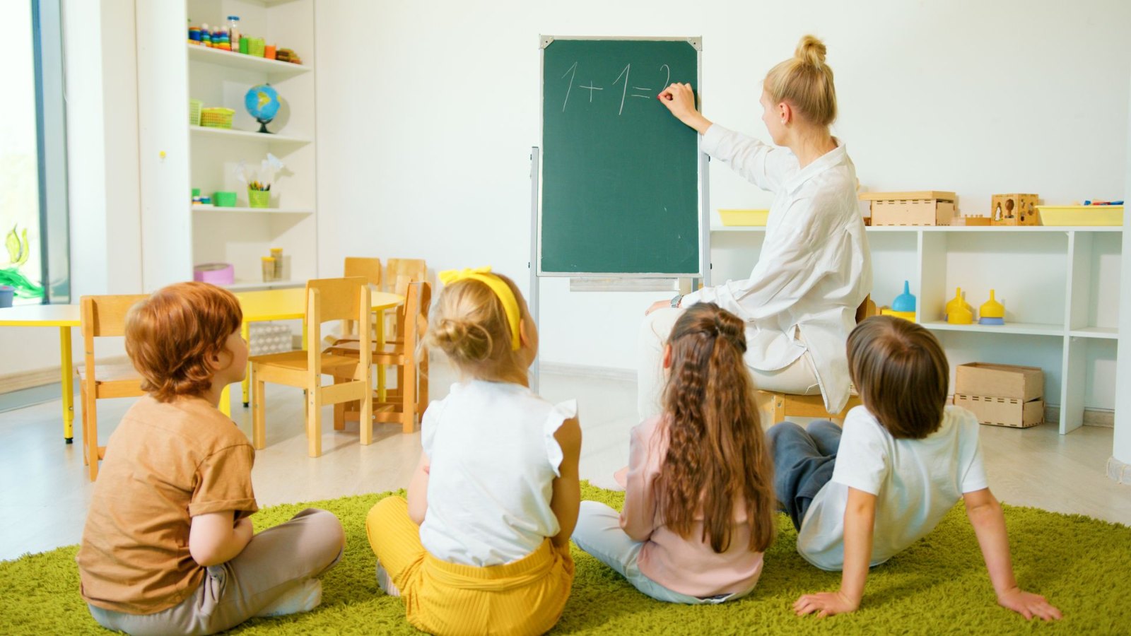 黒板の前で先生の話を聞く子どもたち