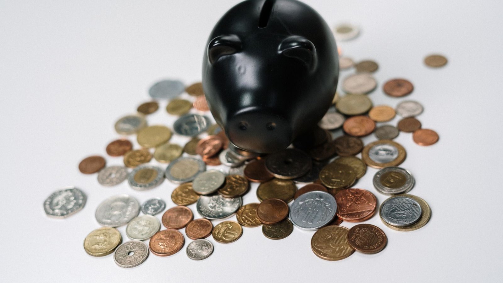 硬貨に囲まれた黒い貯金箱