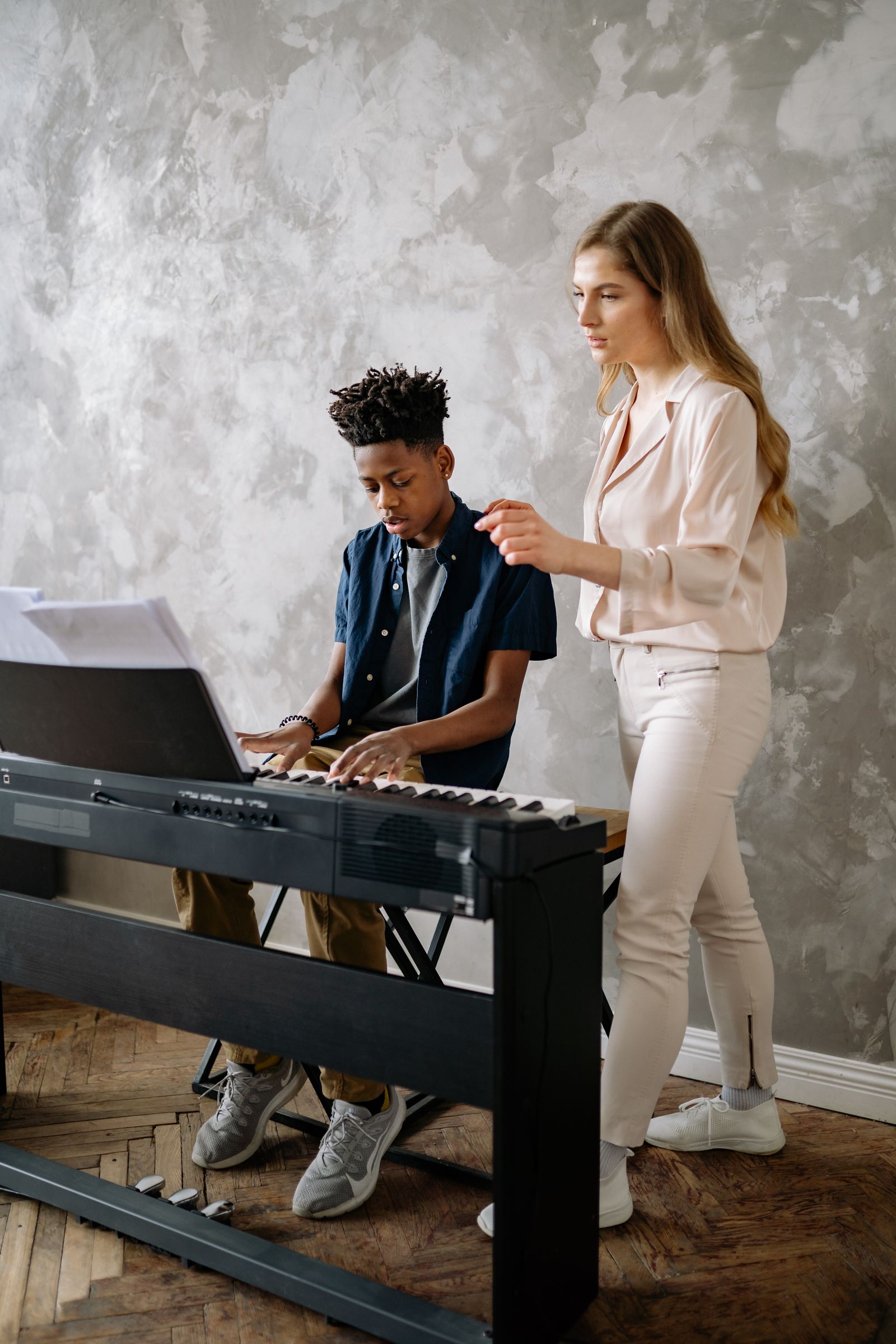 キーボードを弾く男の子を見守る先生。入間市の音楽の習い事のイメージ