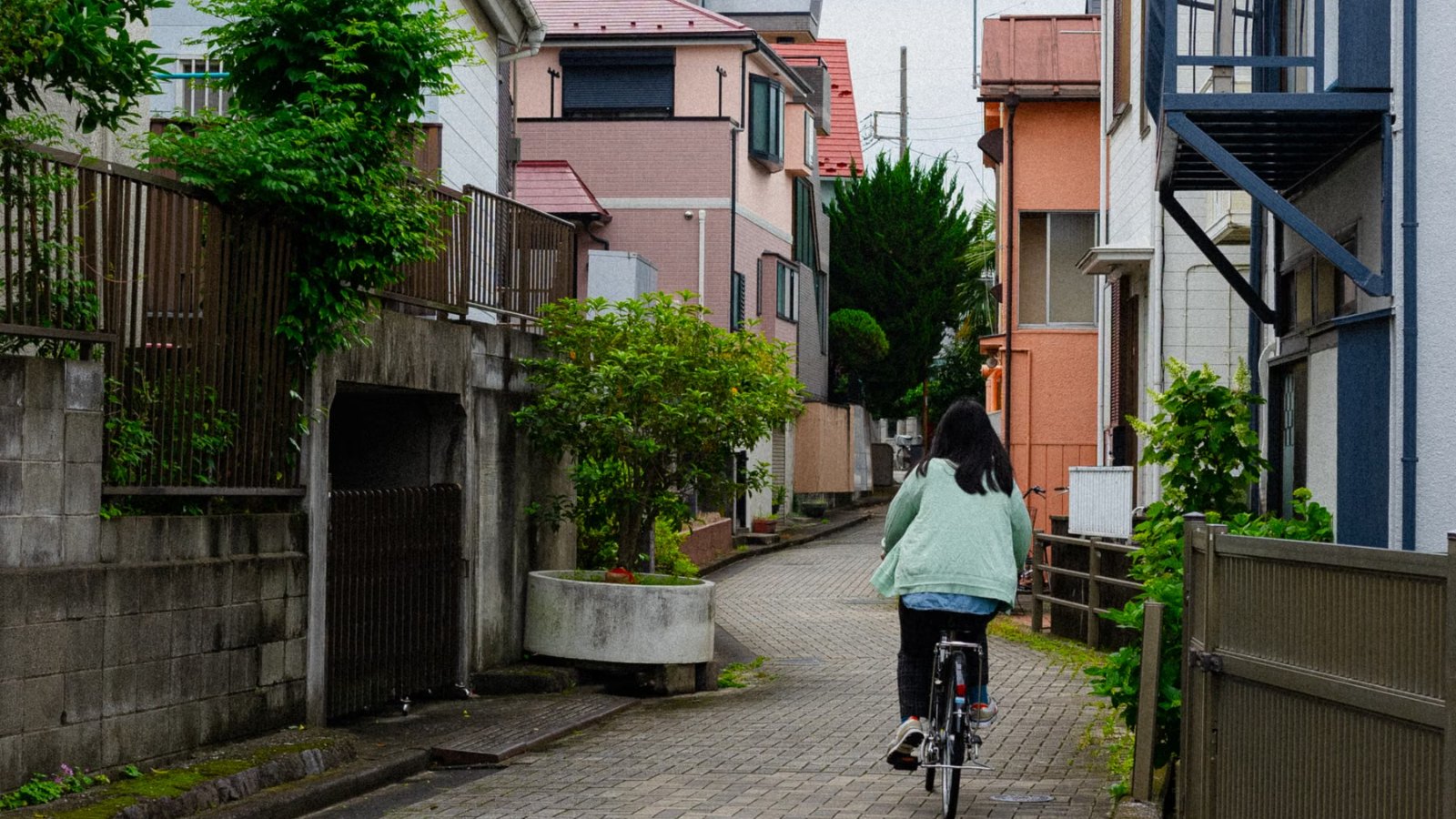 静かな住宅街の道を遠くに自転車で走る人