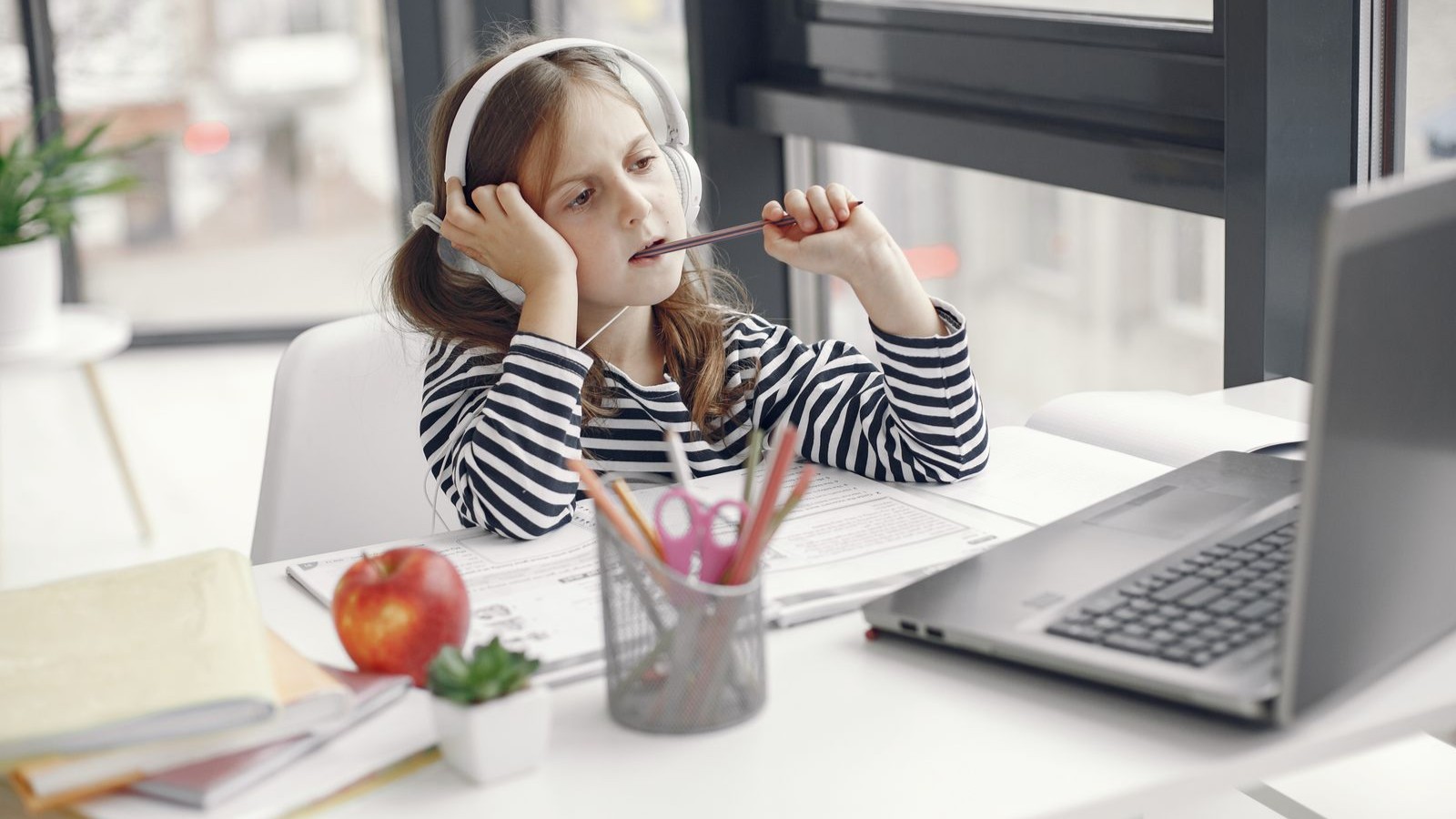 A child wearing headphones working at a laptop at home